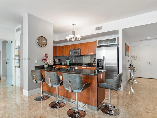 kitchen featuring a kitchen bar, appliances with stainless steel finishes, pendant lighting, backsplash, and a chandelier