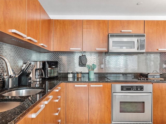 kitchen featuring tasteful backsplash, appliances with stainless steel finishes, sink, and dark stone countertops