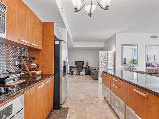 kitchen with dark stone countertops, appliances with stainless steel finishes, tasteful backsplash, and light tile patterned floors