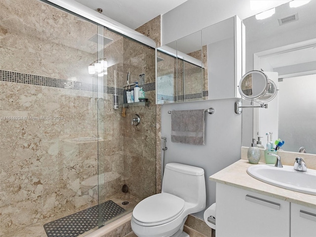 bathroom with a shower with shower door, vanity, and toilet