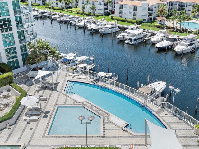 view of swimming pool featuring a dock, a water view, and a patio area