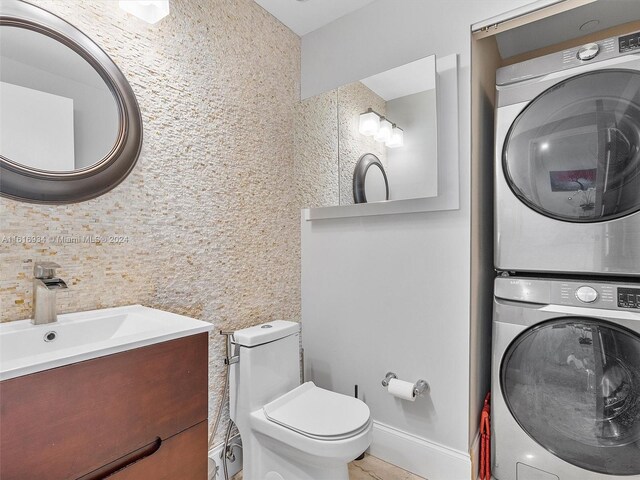 bathroom with stacked washing maching and dryer, toilet, vanity, and tasteful backsplash