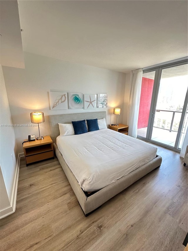 bedroom featuring access to outside, light hardwood / wood-style floors, and floor to ceiling windows