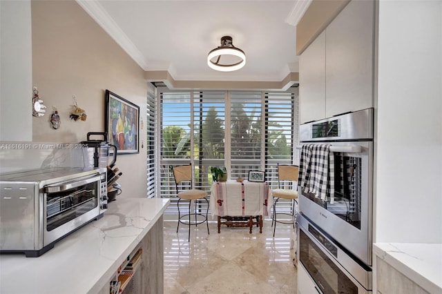 kitchen with a toaster, ornamental molding, light stone counters, marble finish floor, and double oven