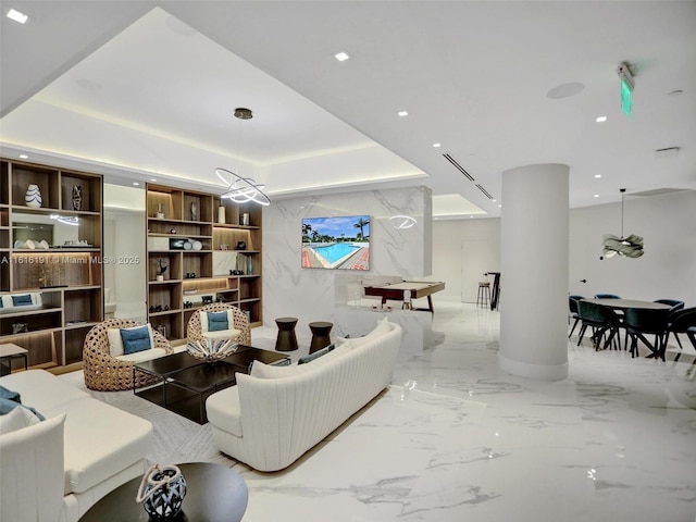 living area with stone wall, a tray ceiling, marble finish floor, and recessed lighting