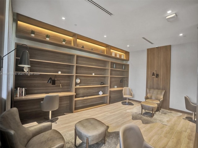 living area with wood finished floors, visible vents, and baseboards