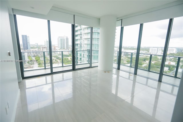 unfurnished room with a healthy amount of sunlight, tile patterned flooring, and floor to ceiling windows