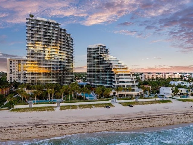 outdoor building at dusk featuring a beach view and a water view