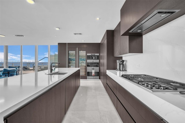 kitchen with light tile patterned flooring, appliances with stainless steel finishes, sink, a water view, and custom range hood