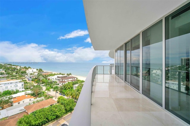 balcony with a water view and a view of the beach