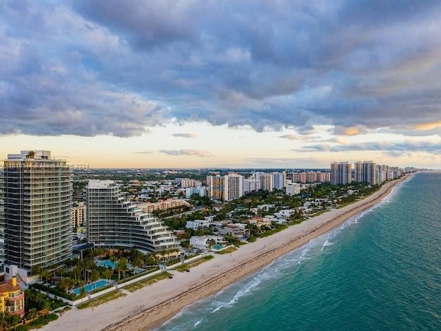 aerial view at dusk with a beach view and a water view