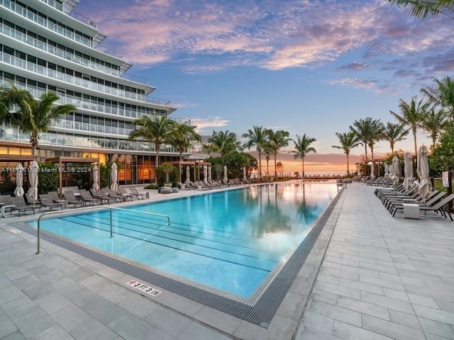 pool at dusk with a water view and a patio