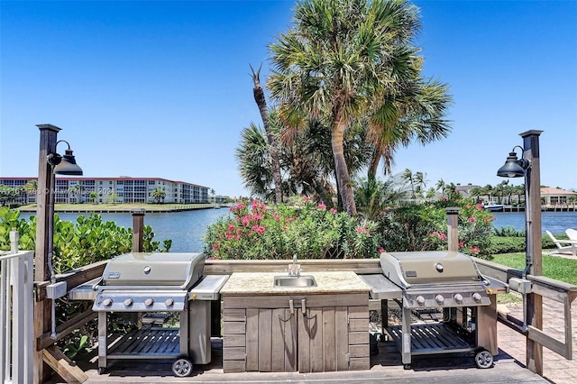 view of patio / terrace with sink, a water view, and grilling area