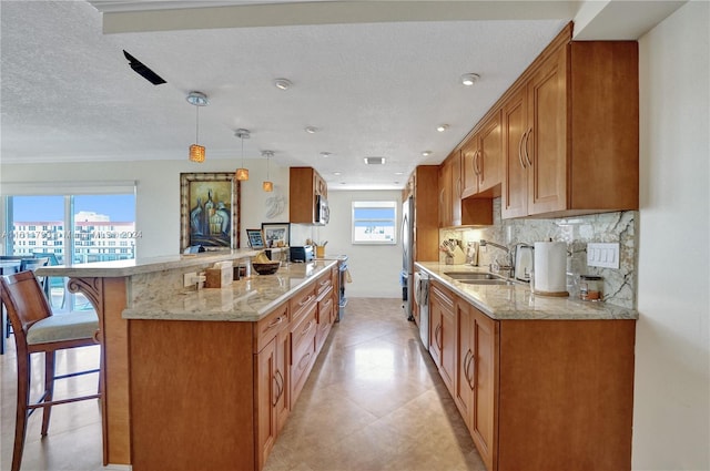 kitchen featuring light tile patterned flooring, a healthy amount of sunlight, decorative light fixtures, and a textured ceiling