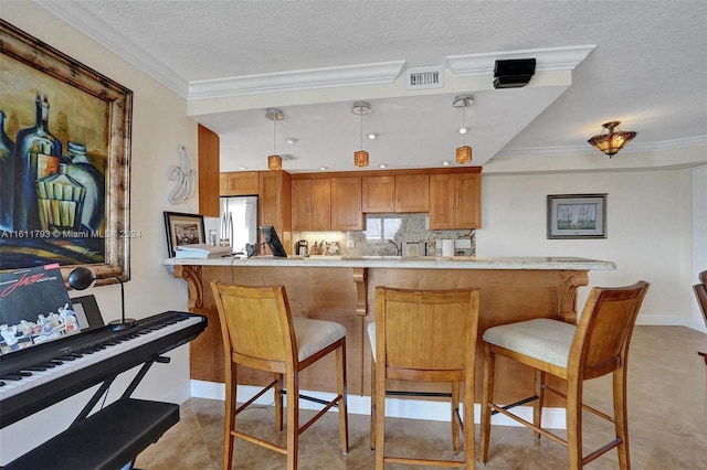 kitchen with light tile patterned flooring, kitchen peninsula, hanging light fixtures, and ornamental molding