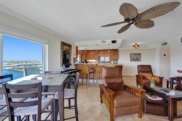 tiled living room featuring ceiling fan, a water view, crown molding, sink, and a textured ceiling