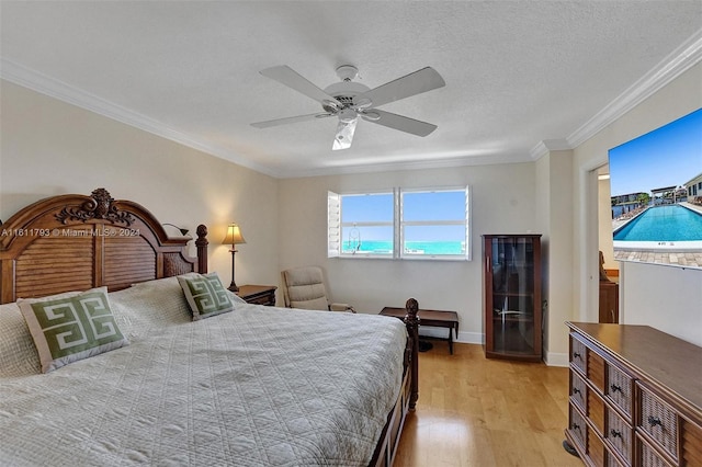 bedroom featuring light hardwood / wood-style flooring, a textured ceiling, ceiling fan, and ornamental molding