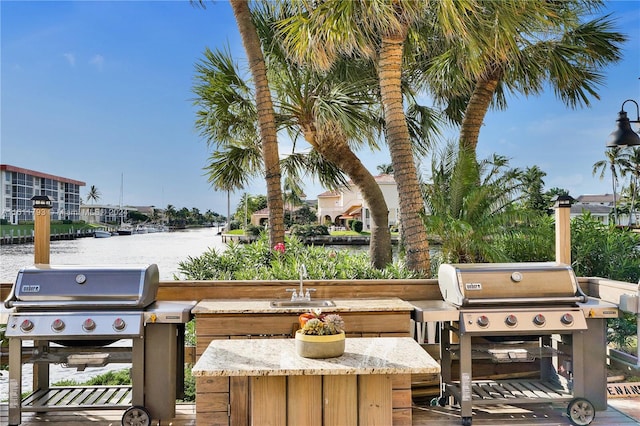 exterior space with sink, a water view, and area for grilling