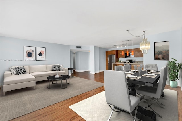 dining space with track lighting, hardwood / wood-style floors, and an inviting chandelier