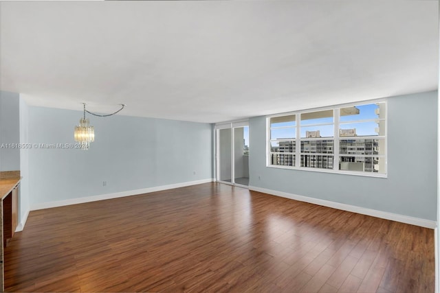 unfurnished room with a notable chandelier and dark hardwood / wood-style flooring