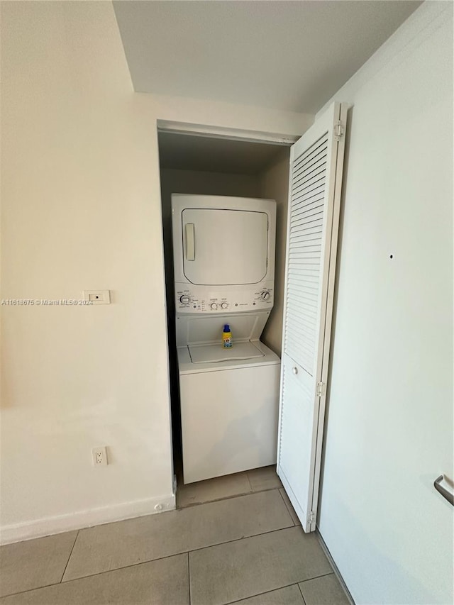 laundry area with stacked washing maching and dryer and light tile patterned floors