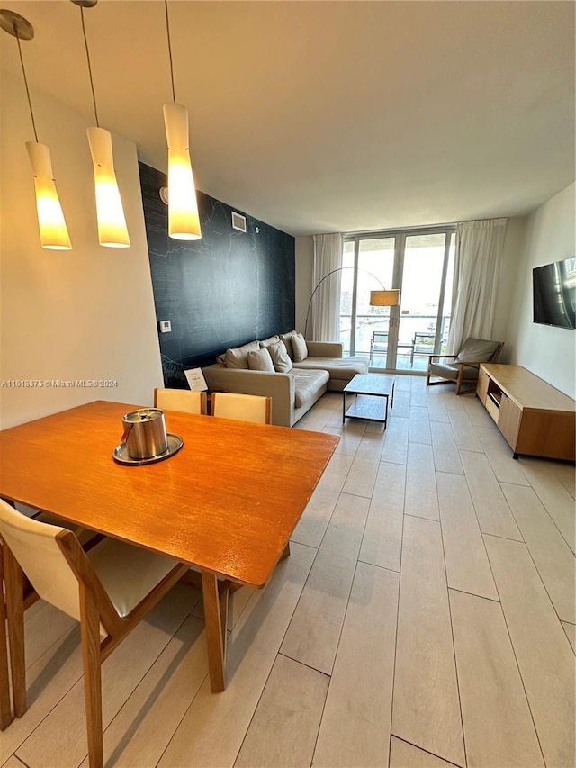 dining space with a wall of windows and light hardwood / wood-style flooring