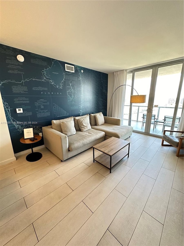 unfurnished living room with expansive windows, light hardwood / wood-style floors, and french doors