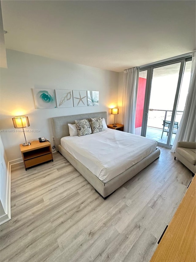 bedroom featuring expansive windows, access to exterior, and light hardwood / wood-style flooring