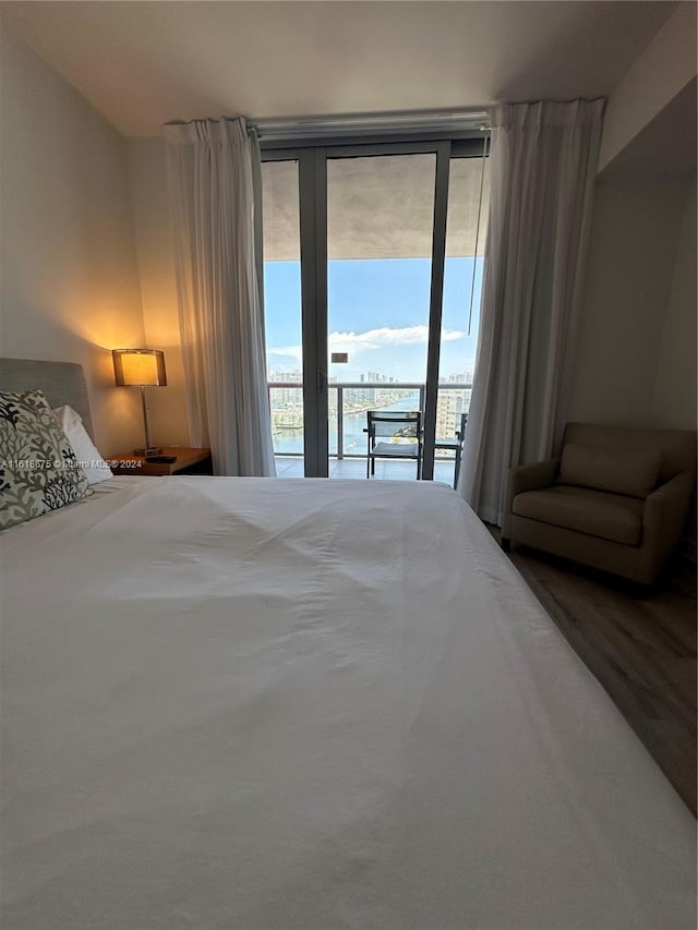 bedroom with access to outside, wood-type flooring, and a water view