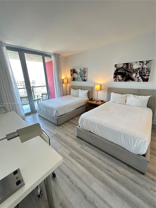 bedroom with expansive windows, access to exterior, and light wood-type flooring