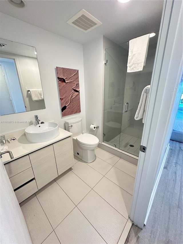 bathroom with tile patterned floors, vanity, toilet, and a shower with shower door