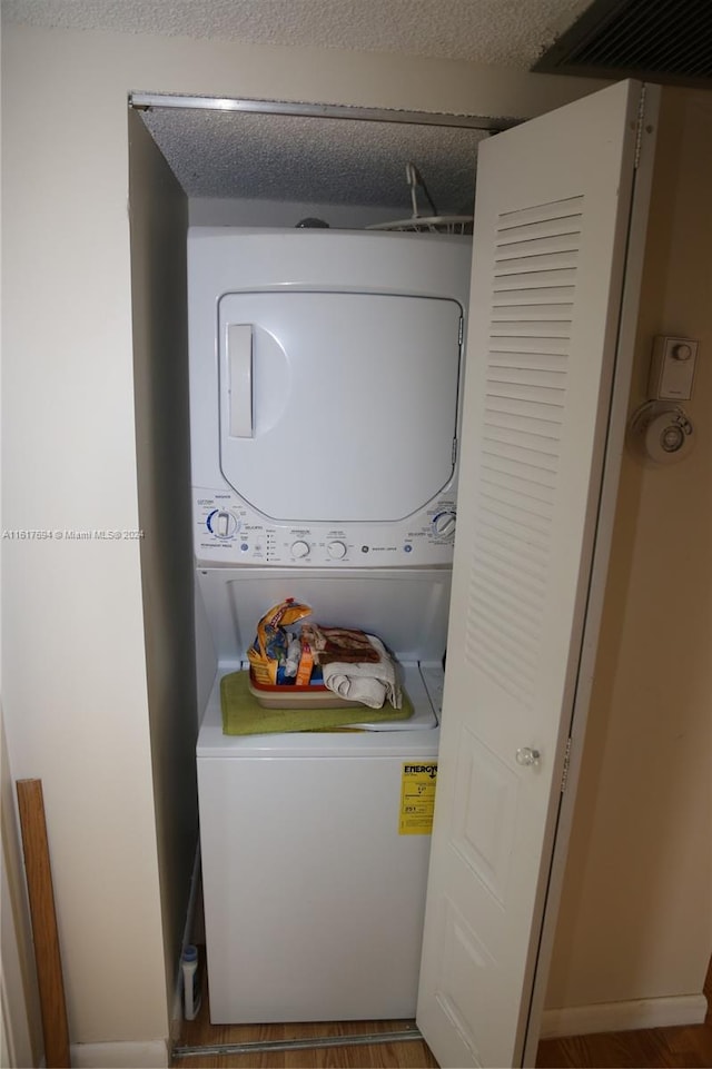 washroom featuring stacked washer and dryer and a textured ceiling