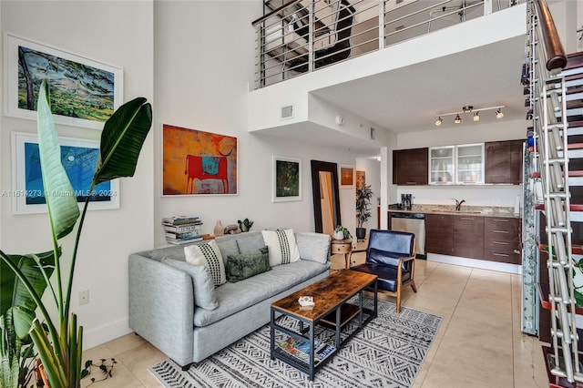 tiled living room featuring sink, a high ceiling, and rail lighting