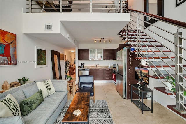 tiled living room with track lighting, sink, and a towering ceiling