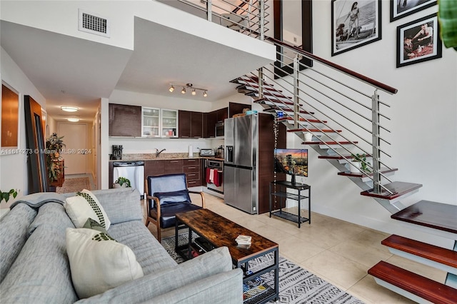 living room featuring sink, light tile patterned flooring, and rail lighting