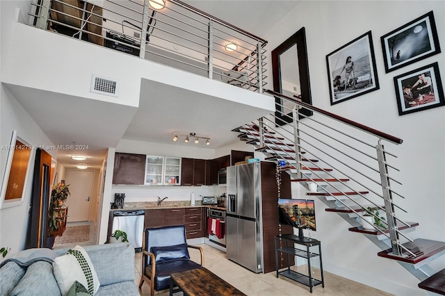 living room with sink, light tile patterned flooring, a high ceiling, and track lighting