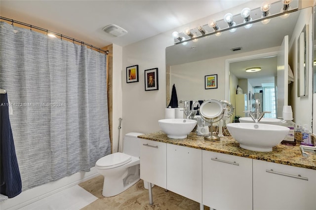 bathroom with tile patterned flooring, double sink vanity, and toilet