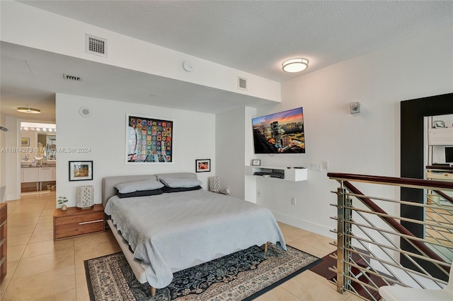 bedroom featuring light tile patterned flooring, connected bathroom, and a textured ceiling