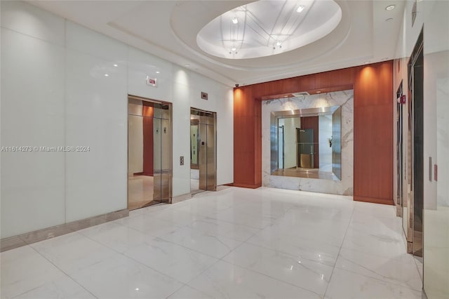 interior space featuring a raised ceiling and elevator