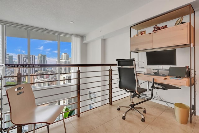 tiled office space featuring expansive windows and a textured ceiling