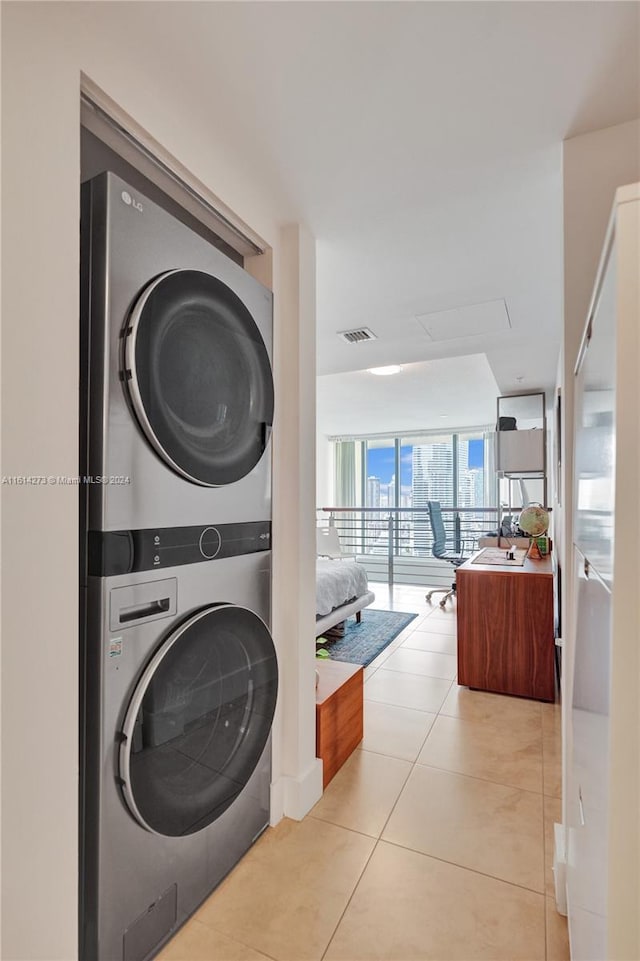 washroom featuring stacked washer / drying machine and light tile patterned floors