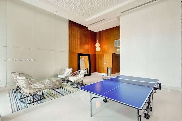 recreation room with wood walls and light tile patterned floors