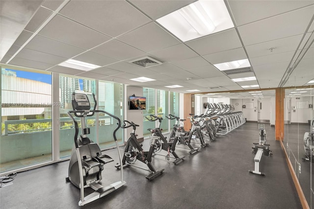 workout area with a wall of windows and a drop ceiling