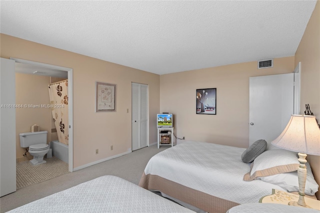 carpeted bedroom with ensuite bath and a textured ceiling