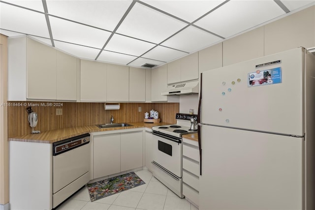 kitchen with light tile patterned floors, sink, cream cabinetry, and white appliances