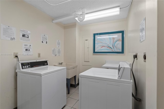 washroom with washer and clothes dryer, light tile patterned flooring, and a textured ceiling