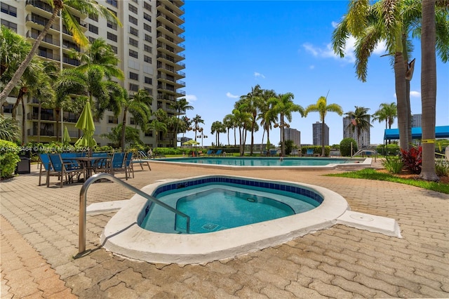 view of pool with a hot tub and a patio