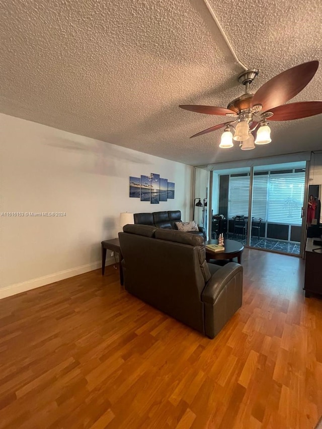 living room with a textured ceiling, wood-type flooring, and ceiling fan