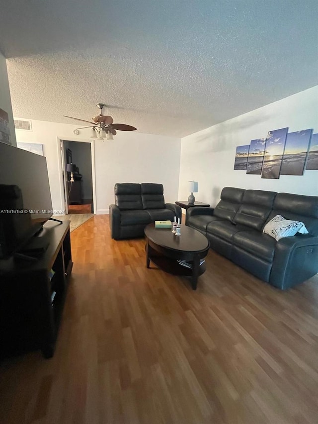 living room featuring ceiling fan, hardwood / wood-style flooring, and a textured ceiling