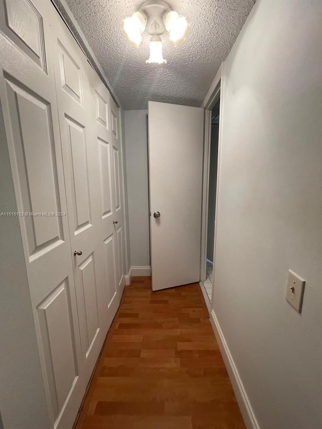 hall featuring hardwood / wood-style flooring, a chandelier, and a textured ceiling